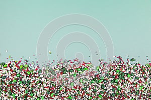 Colorful christmas sprinkles on bottom of pale green background