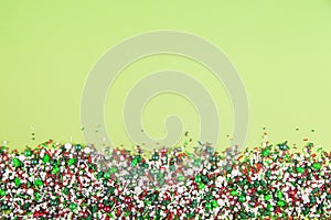 Colorful christmas sprinkles on edge of lime green background