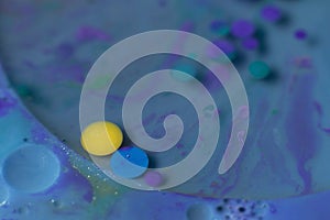 Colorful circles in turquoise liquid with other fluid colors
