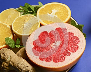 Colorful cirtus slices over blue background. Cut lemons and grapefruit with ginger on a plate