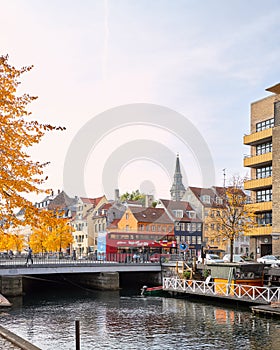 Colorful cityscape at Christianshavn channel with on bridge sightseeing hop on hop off bus passing by with motion blur.