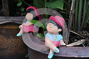 Colorful clay doll boy and girl sitting on the edge of the tree pot.