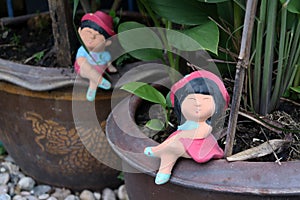 Colorful clay doll boy and girl sitting on the edge of the tree pot.