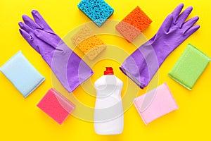 Colorful cleaning set for different surfaces in kitchen on yellow background. Top view, flat lay