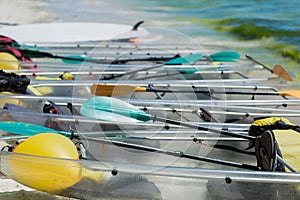 Colorful clear-bottomed rowing boats and surfboards on Boracay\'s sandy beach with palm trees and people in the background