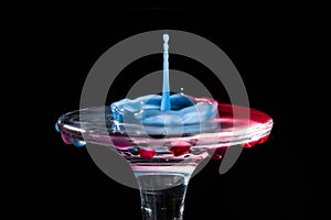 Colorful close-up a red and blue drop in the form of a crown is split on the glass