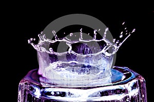 Colorful close-up a violet and blue drop in the form of a crown is split on the glass