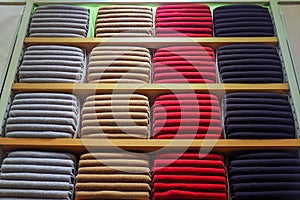 Colorful clothes background .Various color sweaters perfectly folded on a shelf in the shop