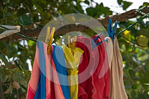 Colorful clothes hanging to dry on a laundry line and sun shining in the blue sky.