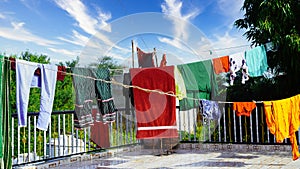 Colorful clothes hanging to dry on a laundry line and sun shining in the blue sky