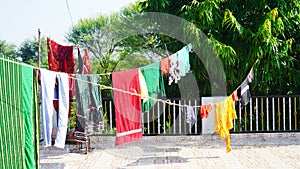 Colorful clothes hanging to dry on a laundry line and sun shining in the blue sky
