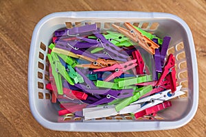 Colorful clothes pegs in plastic basket