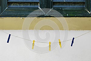 Colorful clothespins clipped to a string against a white wall