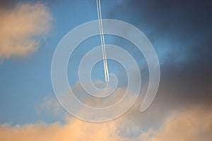 Colorful clouds at dawn, the plane with a trace on a blue background. bright sky filled with sun, the morning of a new day. active