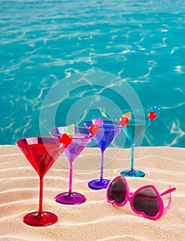 Colorful cocktail in a row with cherry on tropical sand beach