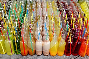 Colorful cocktails, shots with straws in small glass bottles