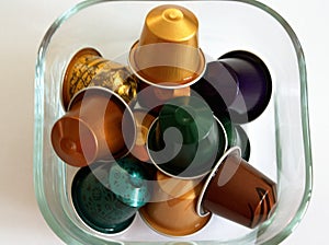 Colorful coffee capsules in a glass bowl.