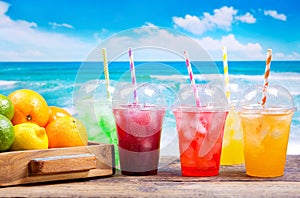 Colorful cold drinks in plastic cups on the beach