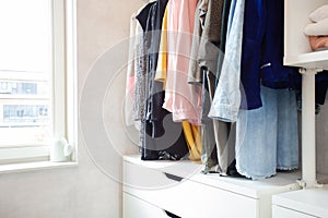 Colorful collection of women's clothes hanging on a rack, modern casual closet in light room , modern dressing room