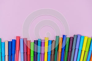 Colorful of color pen isolated on pink background. bright colored markers with caps lie on a pink table