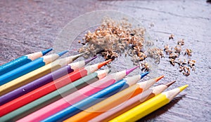 Colorful colorpencil on wooden table in daylight, a broken pencil at the midle of shrapened cyons. coloring wallpaper. education