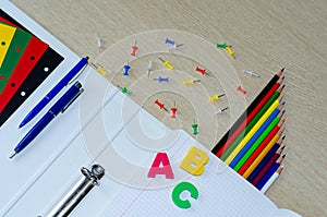 Colorful composition of school supplies and letters on the withe wooden background. Copy space. Flat lay. Back to school
