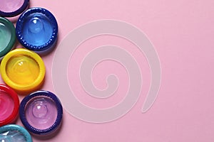 Colorful condoms on pink background, flat lay. Space for text