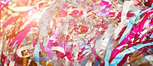 Colorful confetti and streamer lying on floor in fron of background. Festive background of confetti. Blurred glittered background