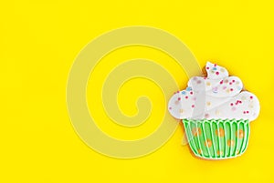 Colorful icing cookie in cupcake shape on yellow background