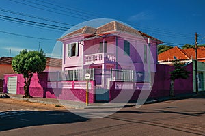 Colorful corner townhouse in an empty street with tree on sidewalk, in a sunny day at San Manuel.