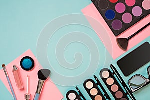 Colorful cosmetics on blue workplace with copy space. Cosmetics make up artist objects: lipstick, eye shadows, powder