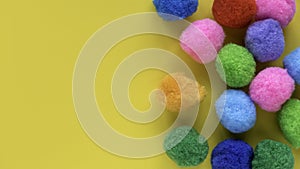Colorful cotton balls on yellow background with copy space