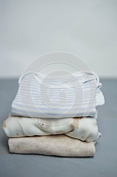 Colorful cotton folded clothes stack on white table empty space background,baby laundry.