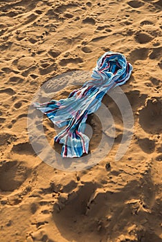 The colorful cotton scarf lays on the sand