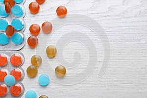 Colorful cough drops on white wooden background, flat lay. Space for text
