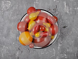 Variety of tomato cultivars in enamel bowl on concrete