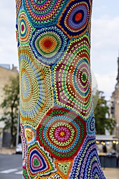 Colorful crochet knit on tree trunk in Kyiv, Ukraine. Street art goes by different names, graffiti knitting, yarn bombing.