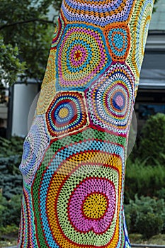 Colorful crochet knit on tree trunk in Kyiv, Ukraine. Street art goes by different names, graffiti knitting, yarn bombing.