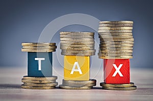 Colorful cube with word TAX and stacking coin on wooden table