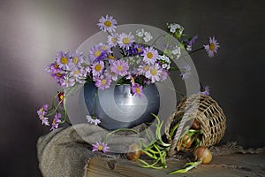 Colorful daisies in a vase and onions on the table