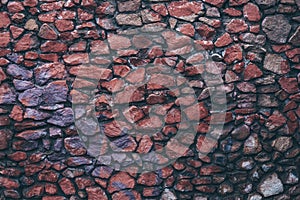 Colorful dark wet stone wall. Texture of painted granite. Uneven rock surface of floor, decorative tile of facade