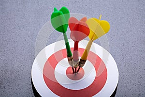 Colorful Darts On Target Against Gray Background photo