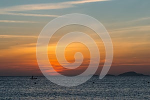 Colorful dawn, sunset on a calm sea. Silhouette of a fishing boat on the horizon.  Beautiful sea background, landscape. Fiery