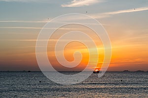 Colorful dawn, sunset on a calm sea. Silhouette of a fishing boat on the horizon.  Beautiful sea background, landscape. Fiery
