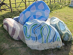 Colorful decorated stone just for show or decorum on green field.