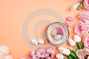 Colorful decorations with Easter egg nest with spring flowers on orange background. copy space, top view