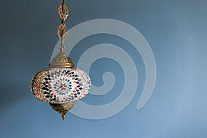 Colorful decorative hanging light against blue wall with copy space.