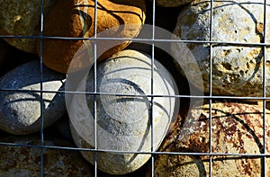 Colorful decorative smooth river stone closeup in galvanized wire mesh cage
