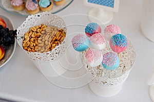 Colorful, delicious lollipops presented in a white bowl, next to peanuts