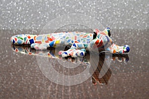 Colorful designer lizard on a glass table. Shining bckground